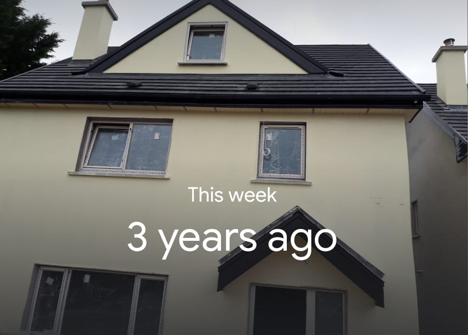 Two-story house with light yellow exterior, black roof, and windows; the text reads 