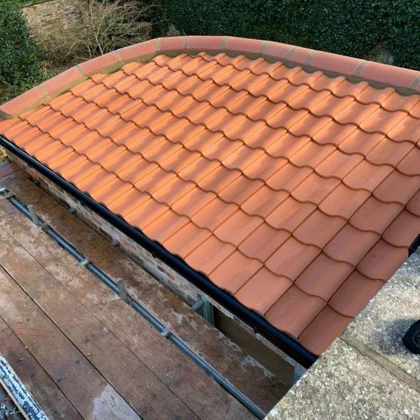 Terracotta-tiled roof with black edging and scaffolding.