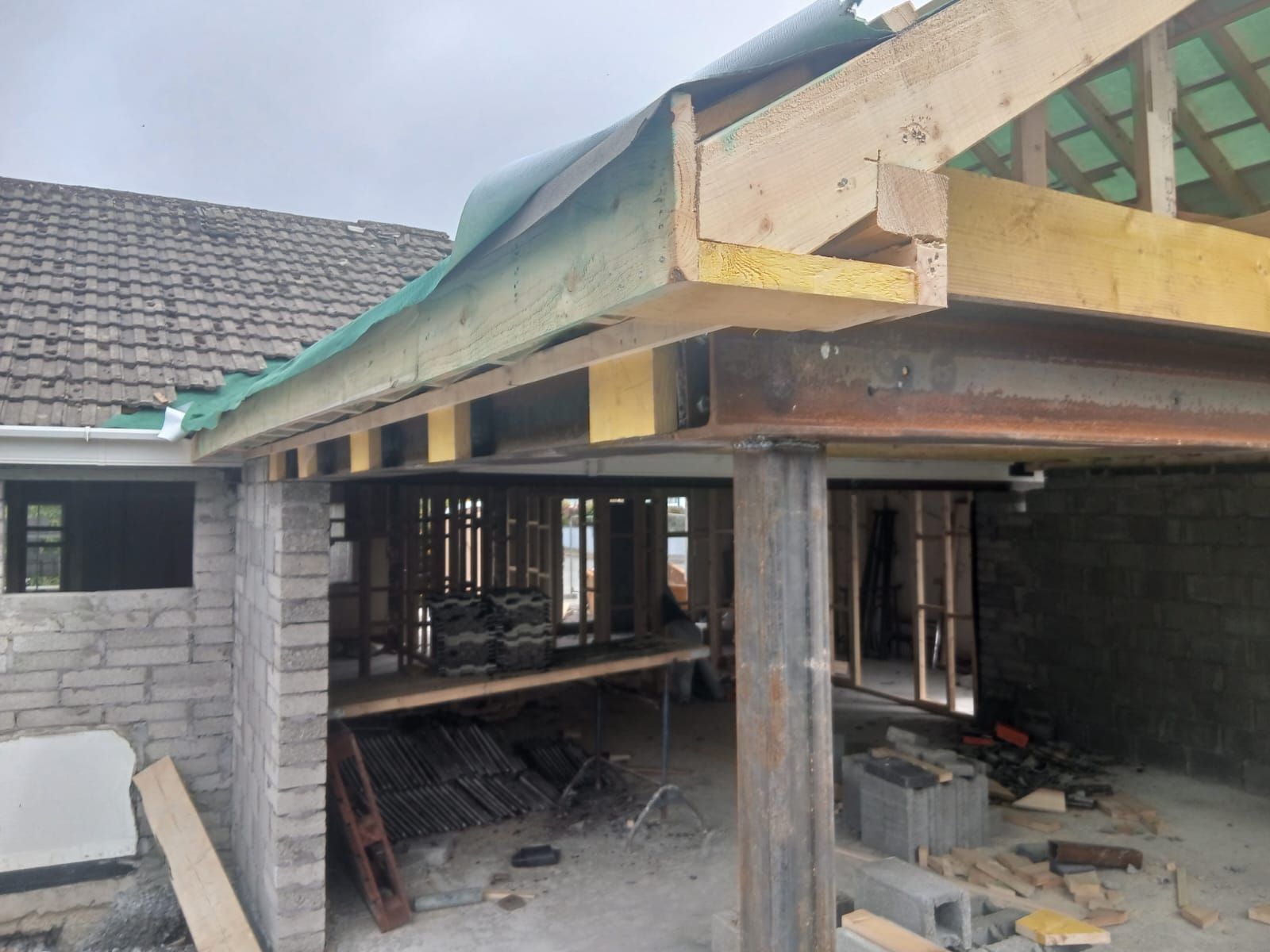 Construction site:  Wooden beams and a steel support frame under a partially built roof.