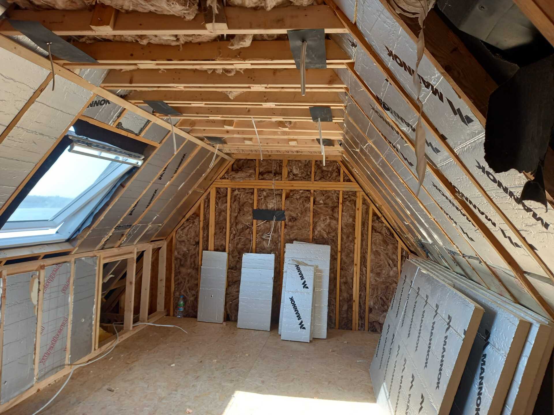 Interior of an attic with wood framing, insulation, and skylight, ready for finishing work.