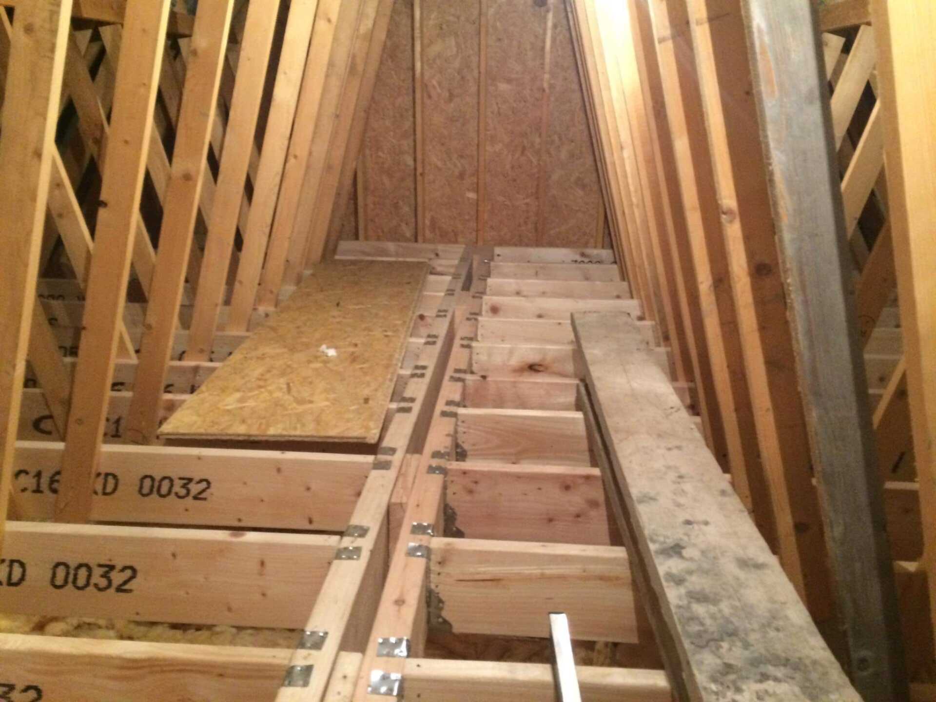 Attic rafters and partially constructed floor with plywood and wooden beams.