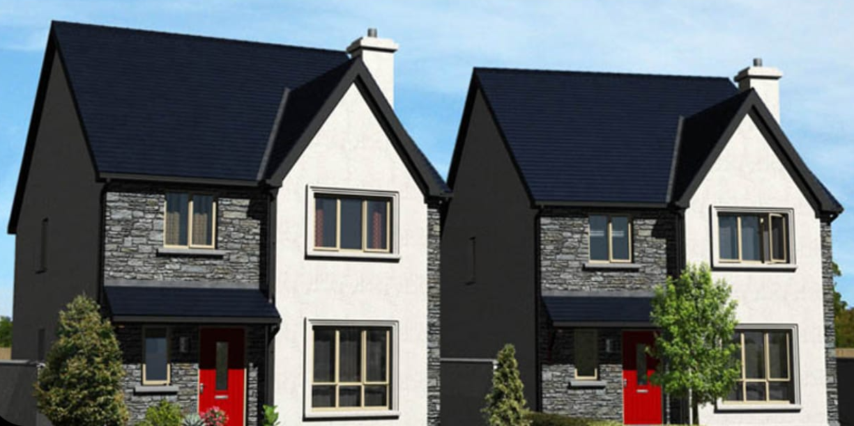 Two white houses with dark roofs, gray stone siding, and red doors under a blue sky.