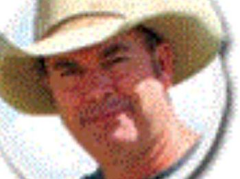 A man wearing a cowboy hat is covering his nose with his hand.