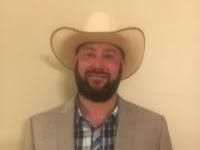 A man with a beard is wearing a cowboy hat and a suit.