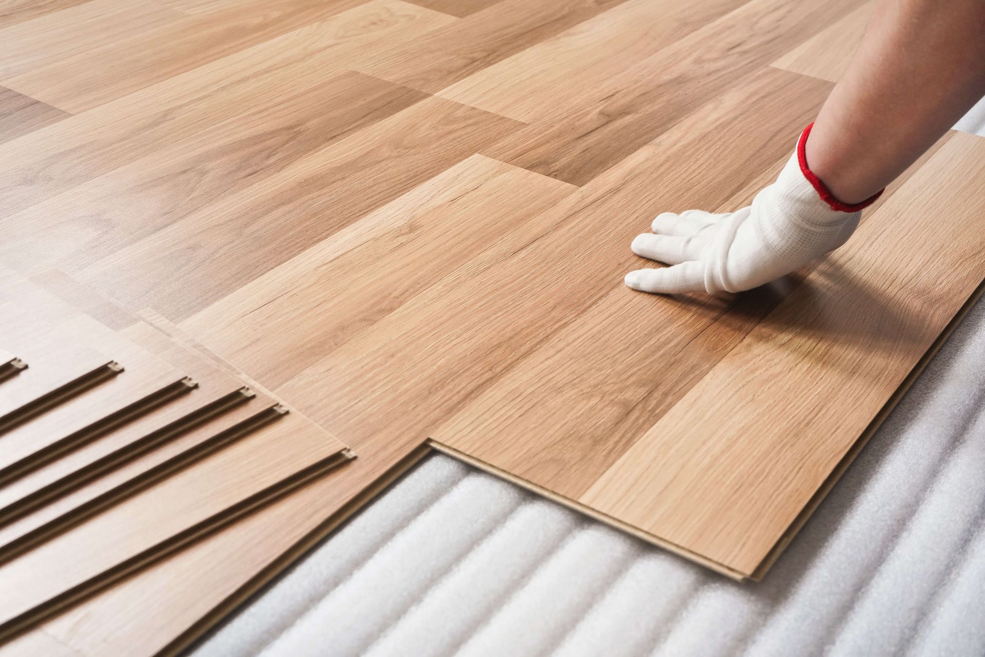 A person is installing a wooden floor in a room.