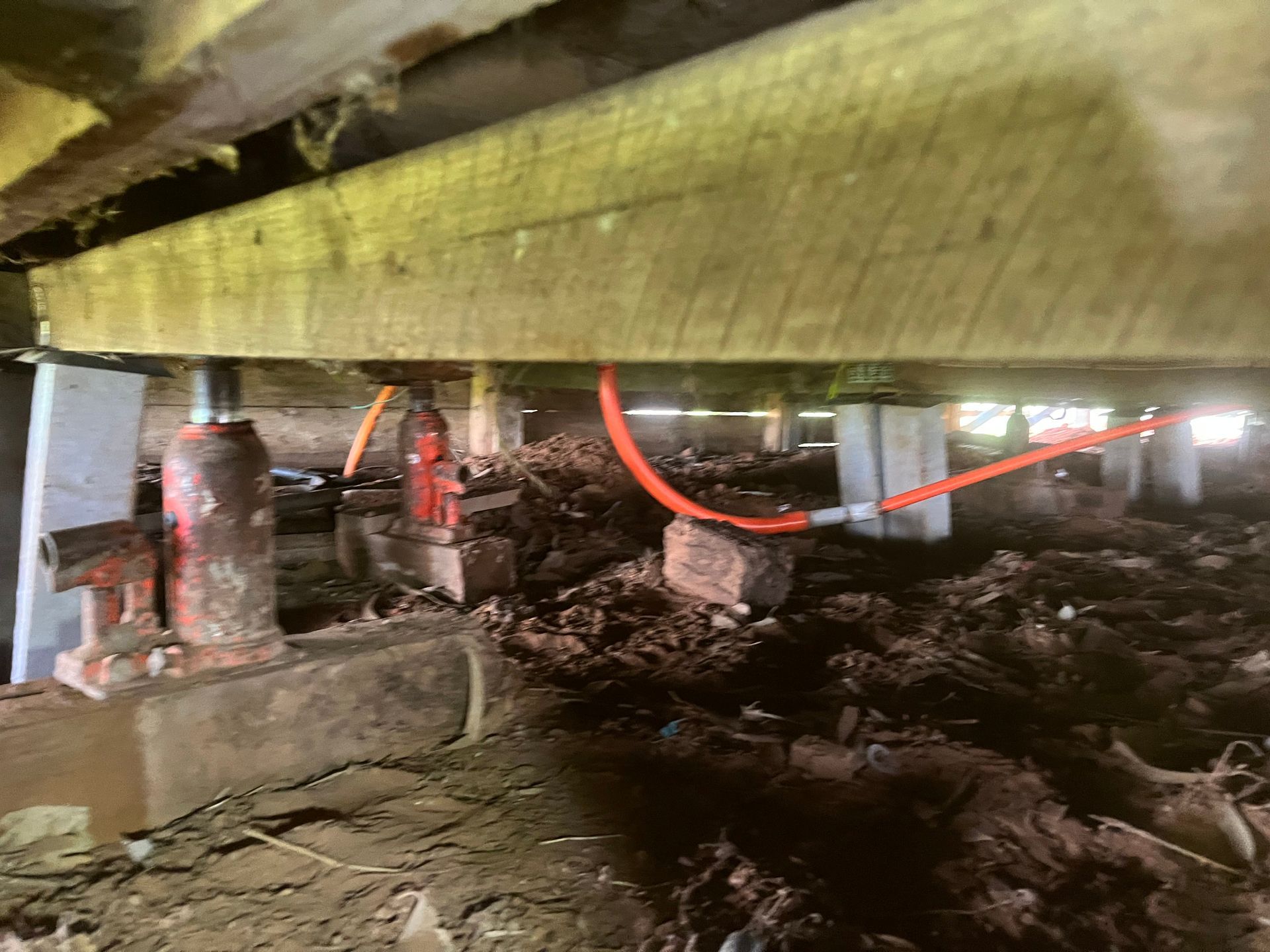 A close up of a hydraulic jack under a house.