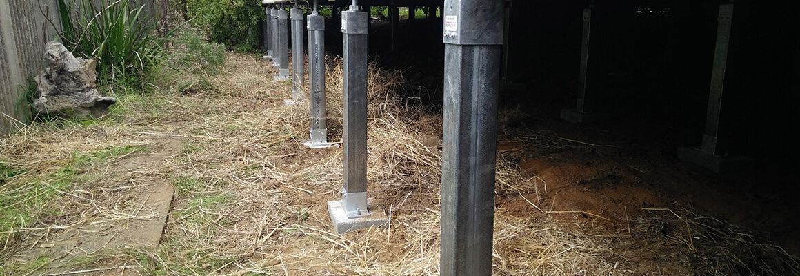 A row of metal poles sitting on top of a dirt field.