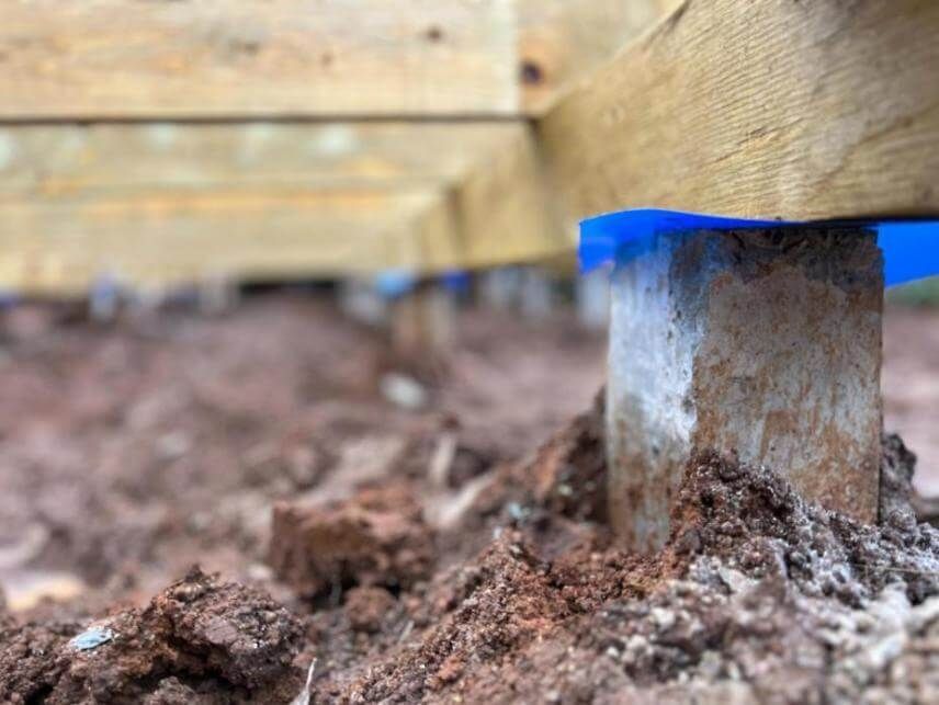 A close up of a wooden post in the dirt.