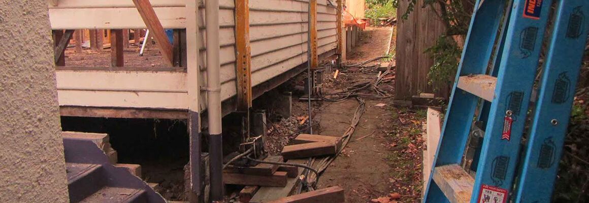 A blue ladder is sitting in front of a house under construction.