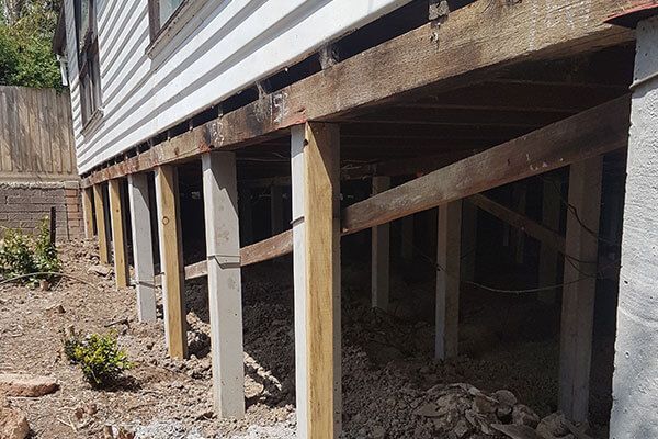 A house is being built on stilts with wooden beams.