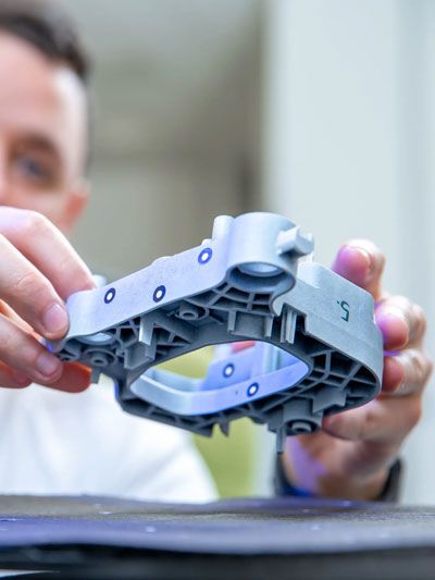 Technician inspecting a complex plastic component for scanning targets.