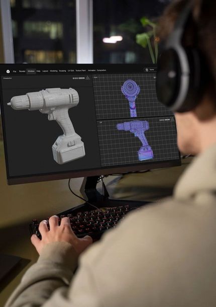 Designer modelling a cordless drill in 3D on a workstation.
