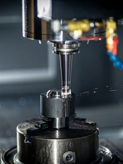 CNC machine precisely milling a metal component, with coolant spraying.