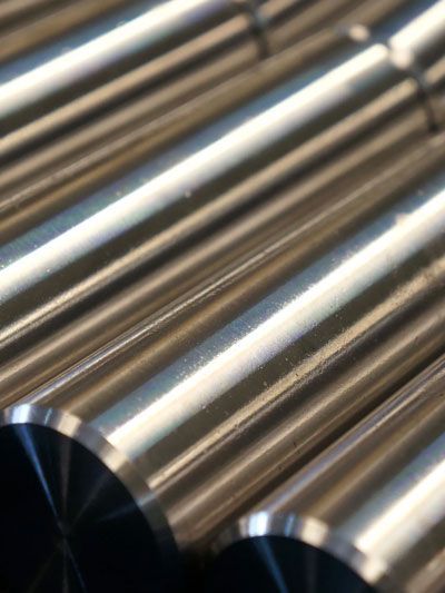 Close-up of several parallel, shiny, metal rods, possibly gear components.
