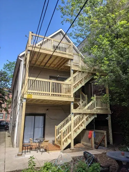 The back of a house with a wooden deck and stairs.