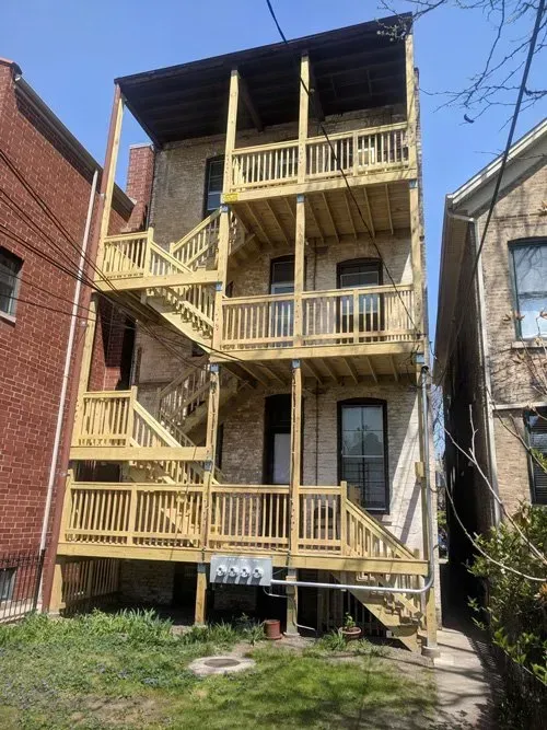 A brick building with a wooden deck and stairs.