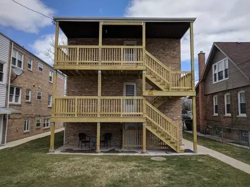 A brick building with a wooden deck and stairs.