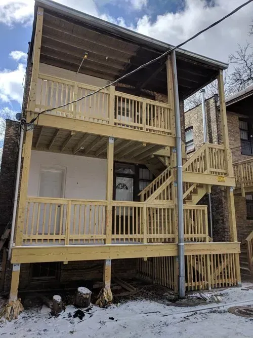 A house with a wooden deck and stairs on the side of it.
