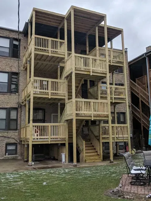 The back of a building with a wooden deck and stairs.