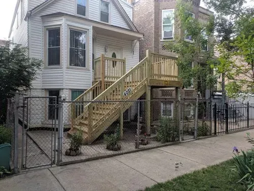 A white house with a wooden deck and stairs.