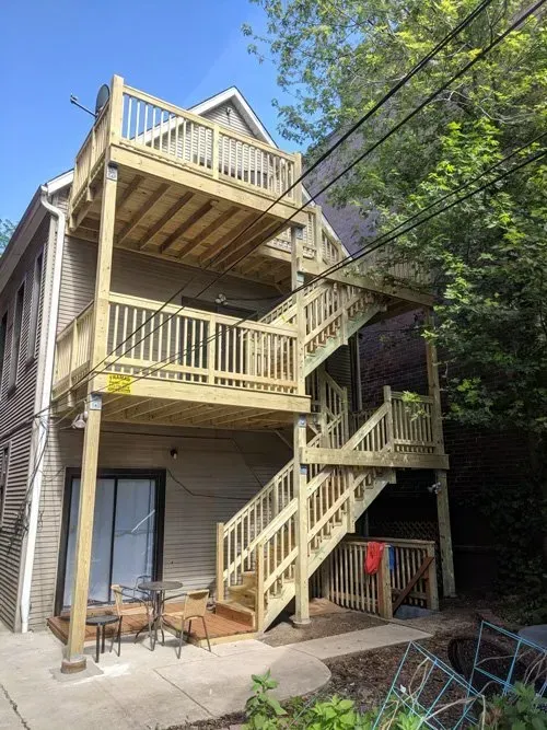 A house with a wooden deck and stairs on the back of it.