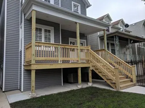 A house with a wooden deck and stairs on the side of it.