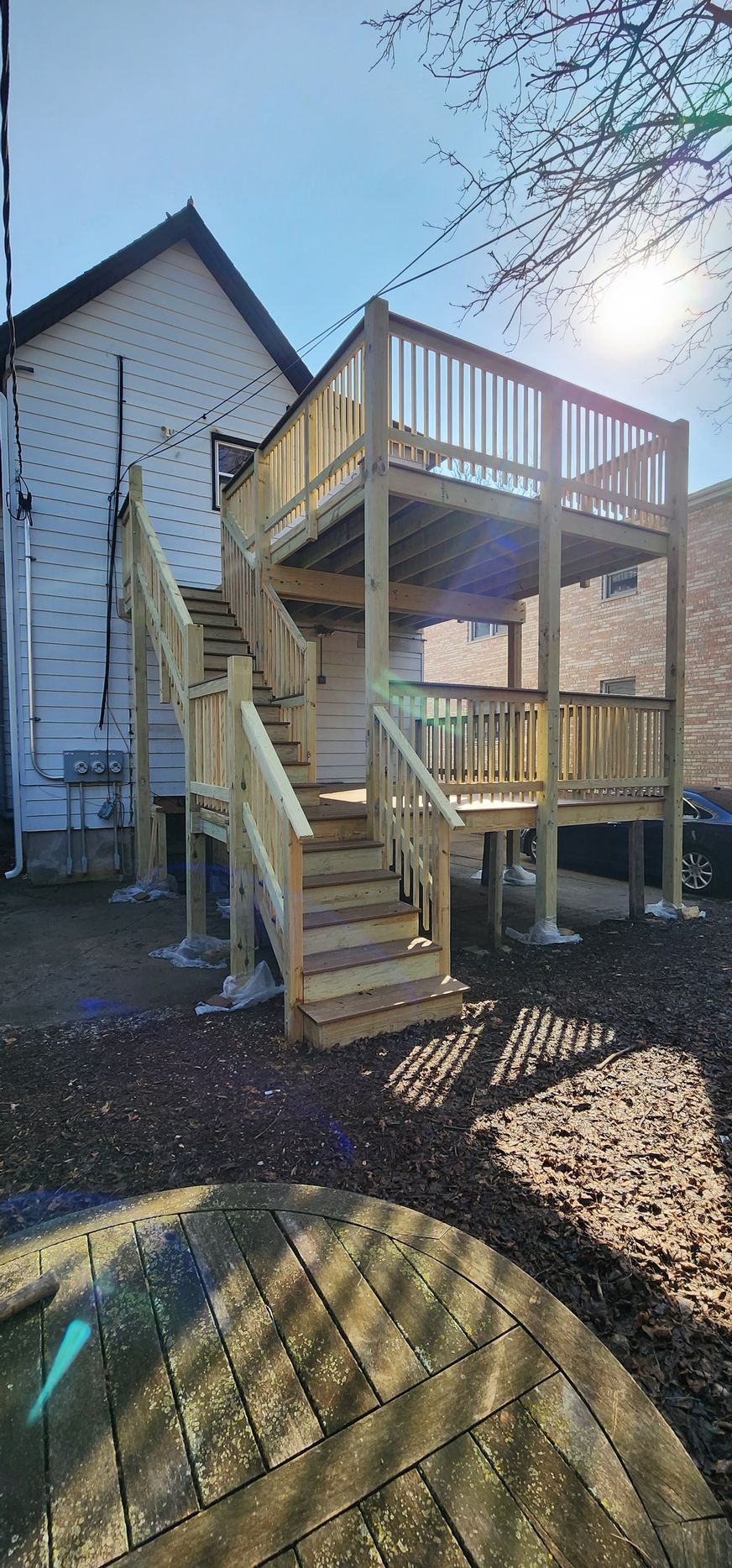 A wooden deck with stairs leading up to it is in front of a house.