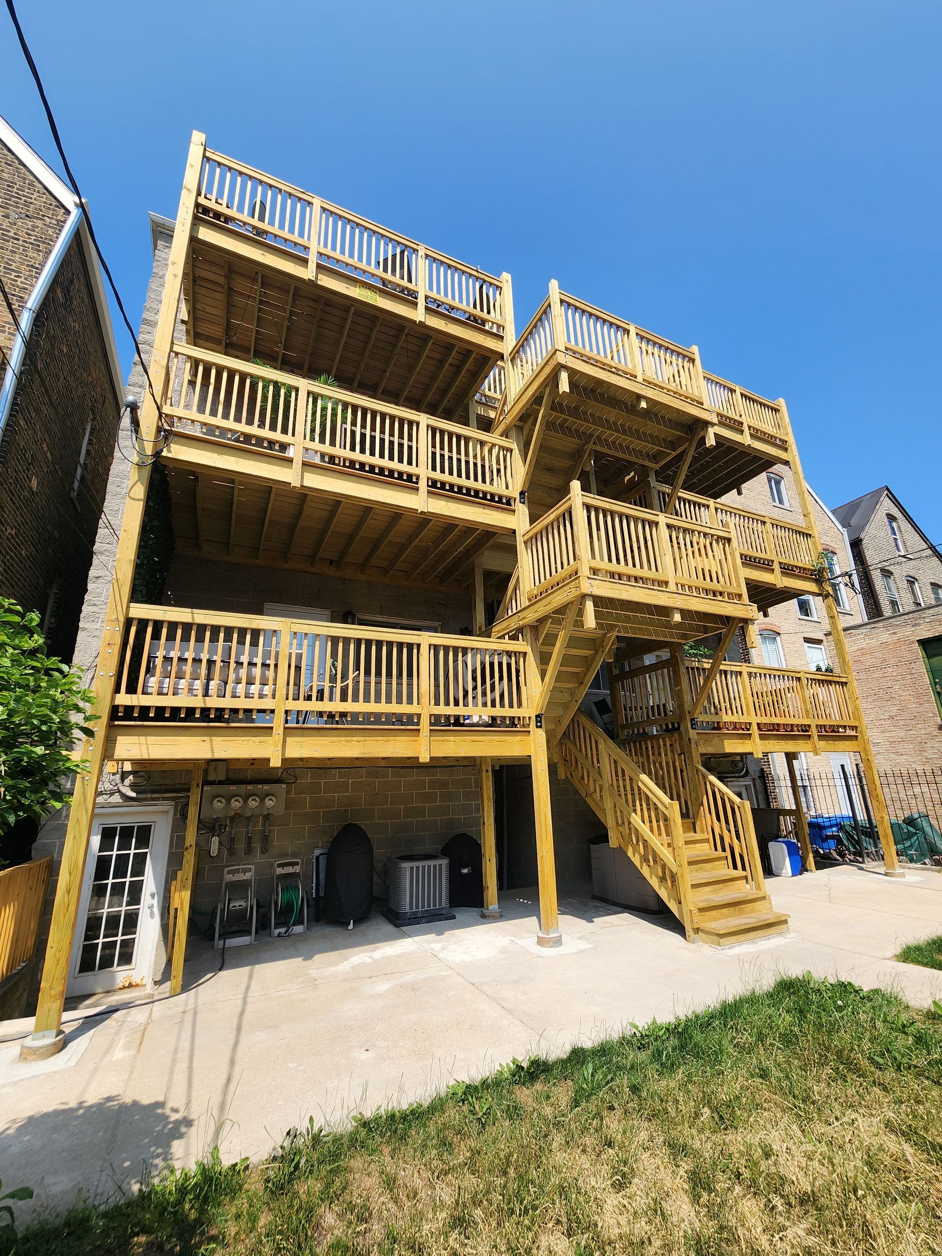 A large wooden deck with stairs on the side of a building.