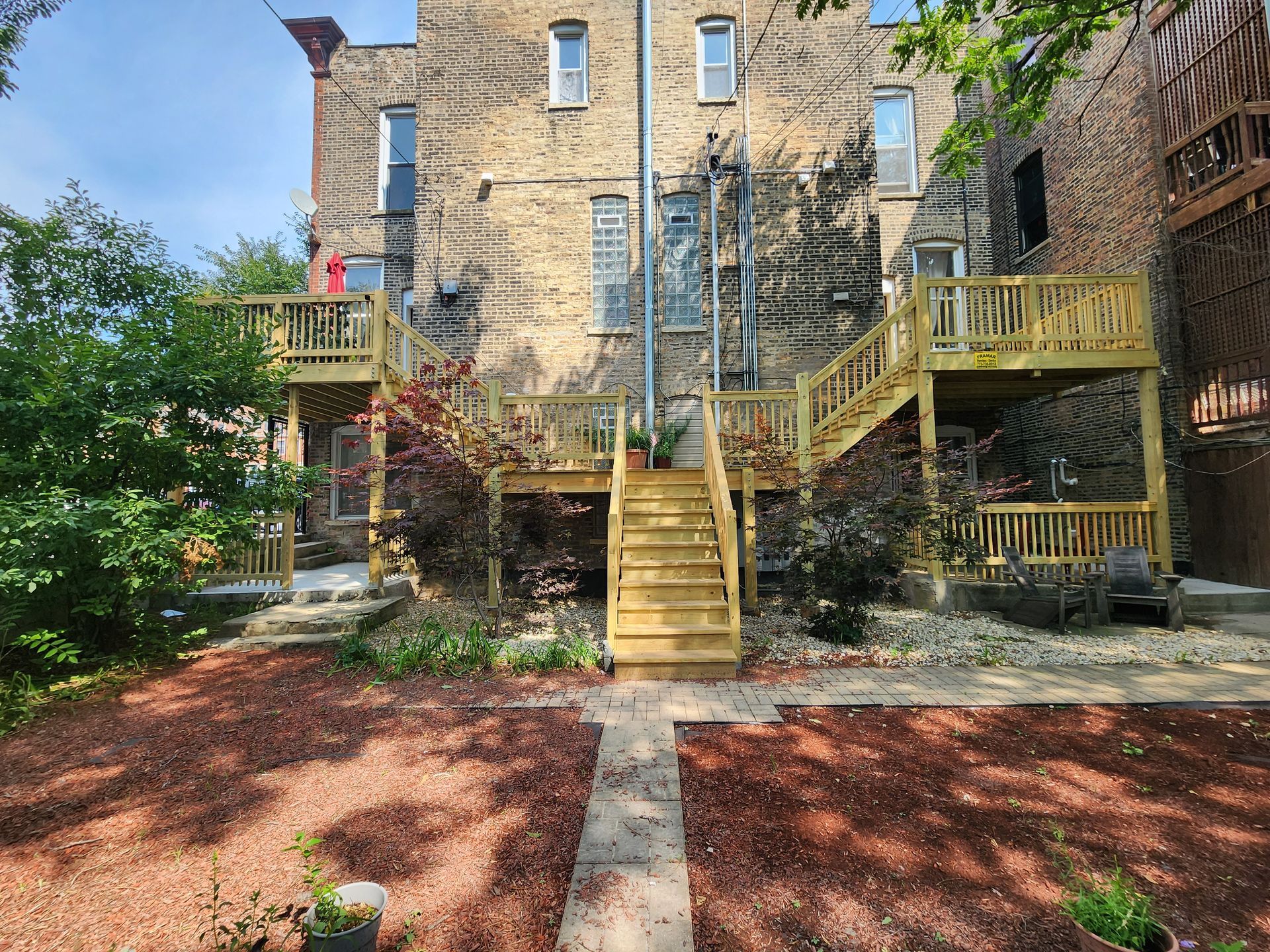 A large brick building with a wooden deck and stairs in front of it.