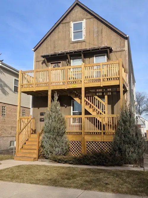 A house with a large wooden deck and stairs.