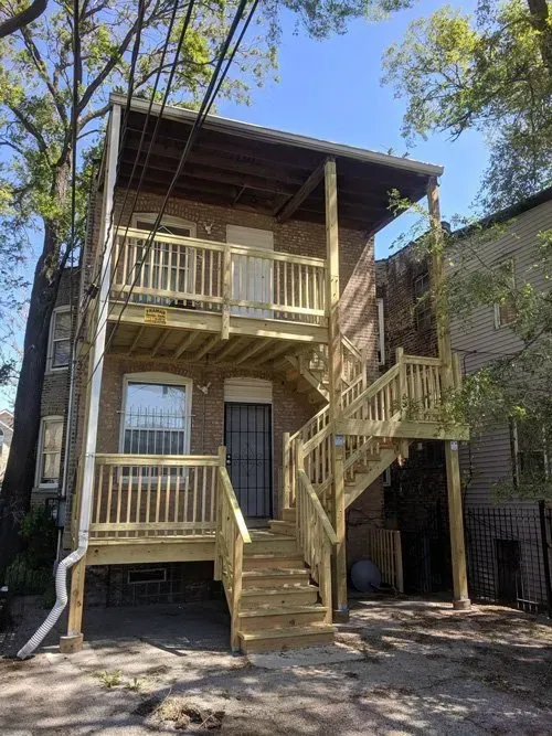 A brick house with a wooden deck and stairs.