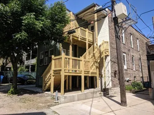 A building with a wooden deck and stairs on the side of it.