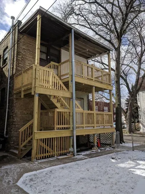 A brick building with a wooden deck and stairs.