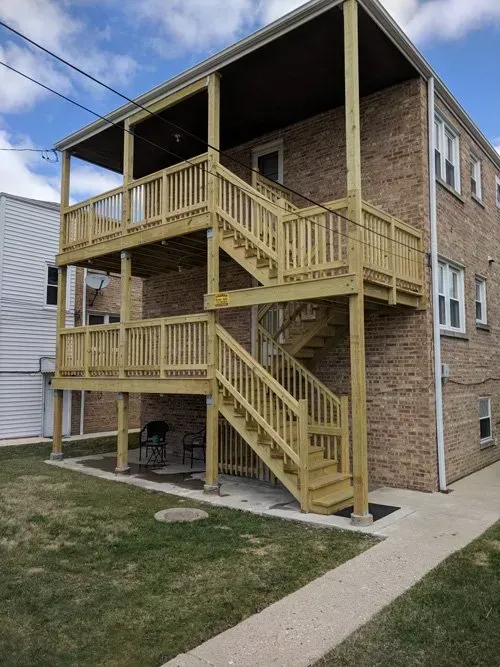 A brick building with a wooden deck and stairs.