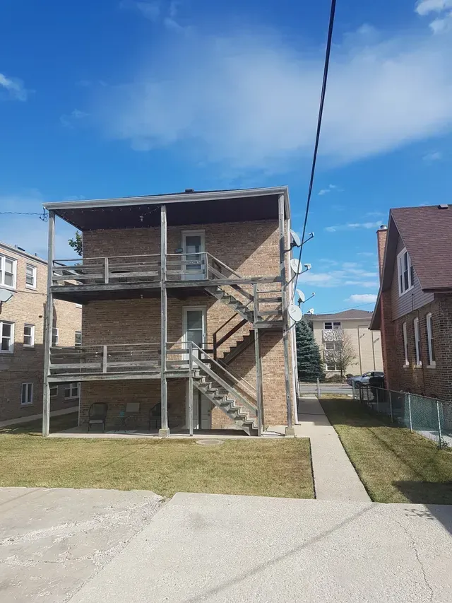 A brick house with stairs leading up to the second floor.