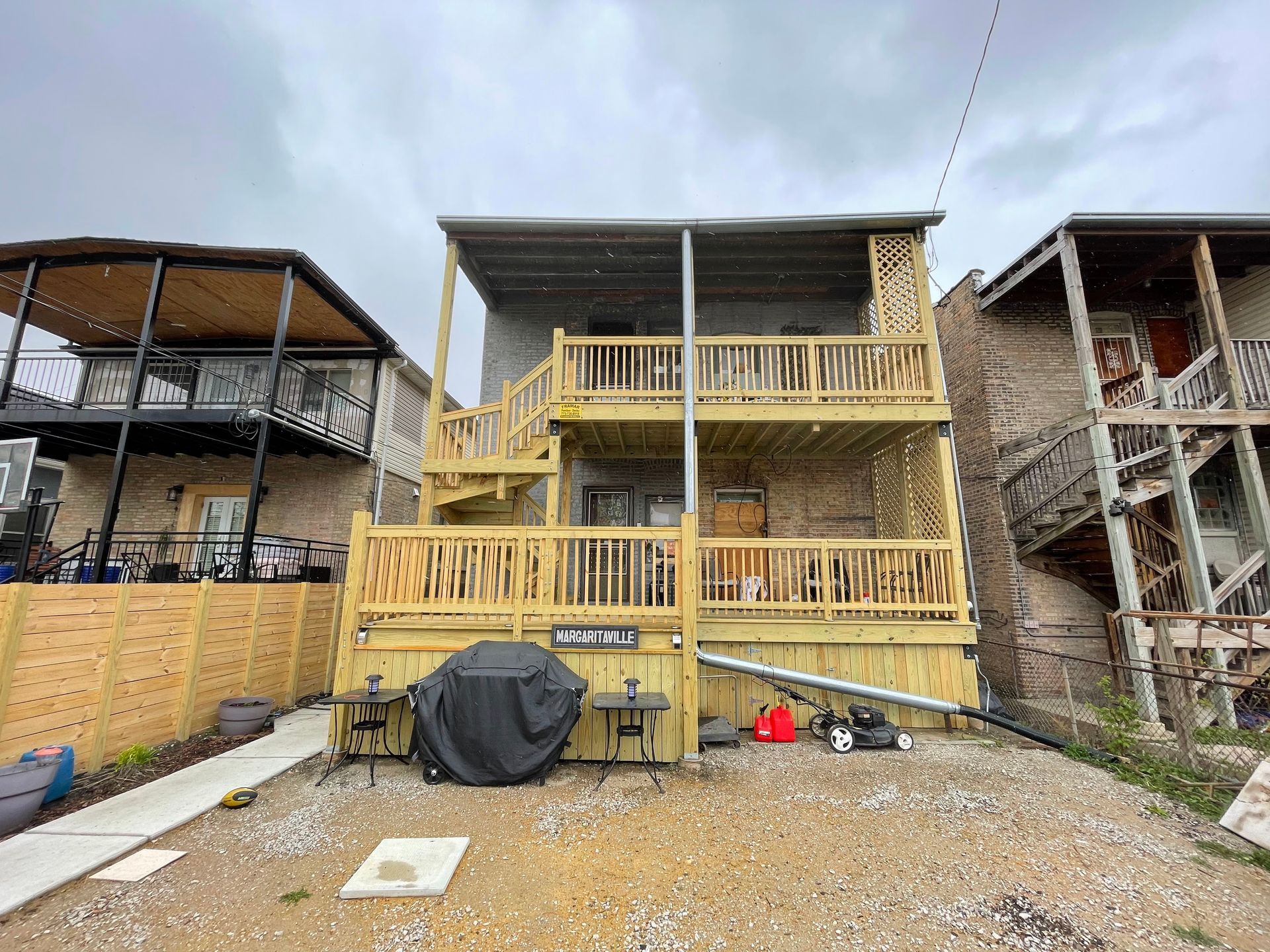 The back of a house with a wooden deck and stairs.