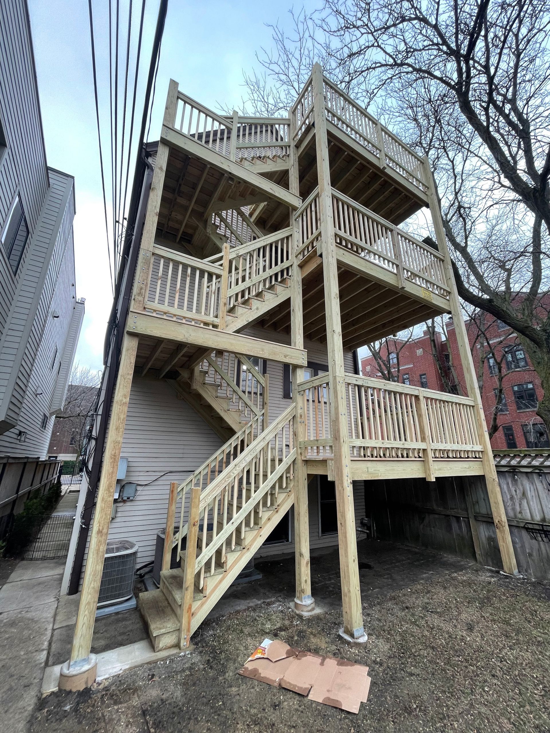 A wooden deck with stairs leading up to it is being built on the side of a house.