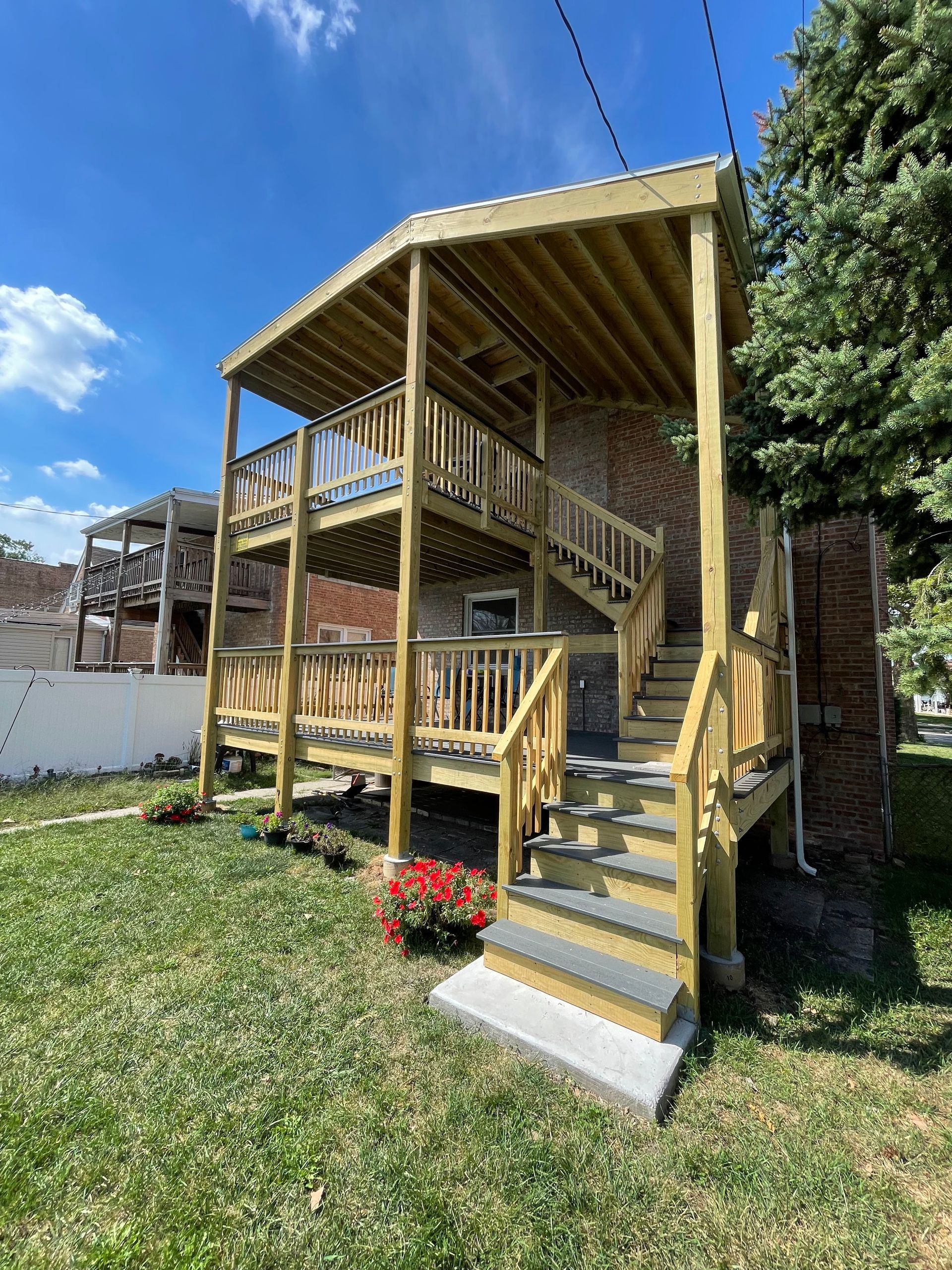 A wooden deck with stairs is in the backyard of a house.