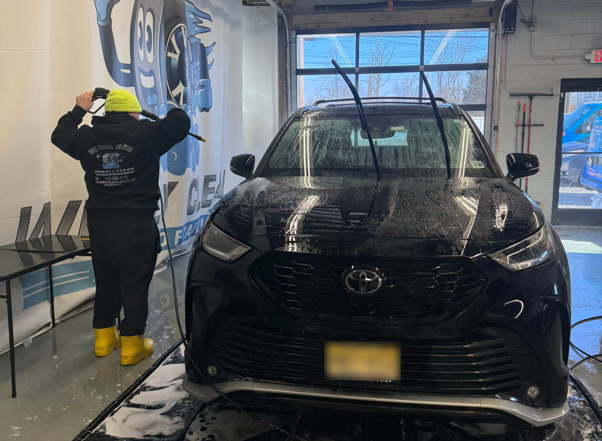 Cream-colored vintage car, rear view, red taillight. Chrome bumper and trim.