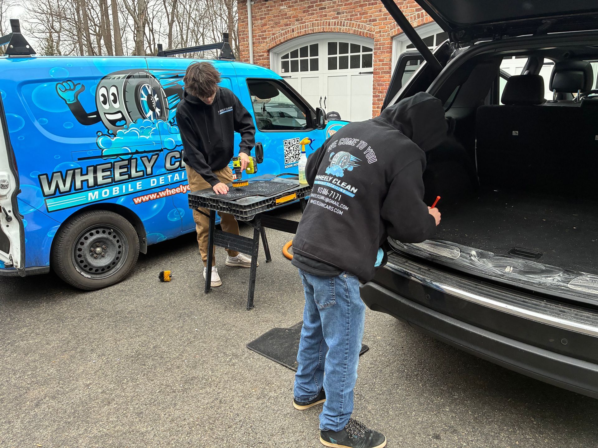 Two people working on a vehicle. A blue van with 