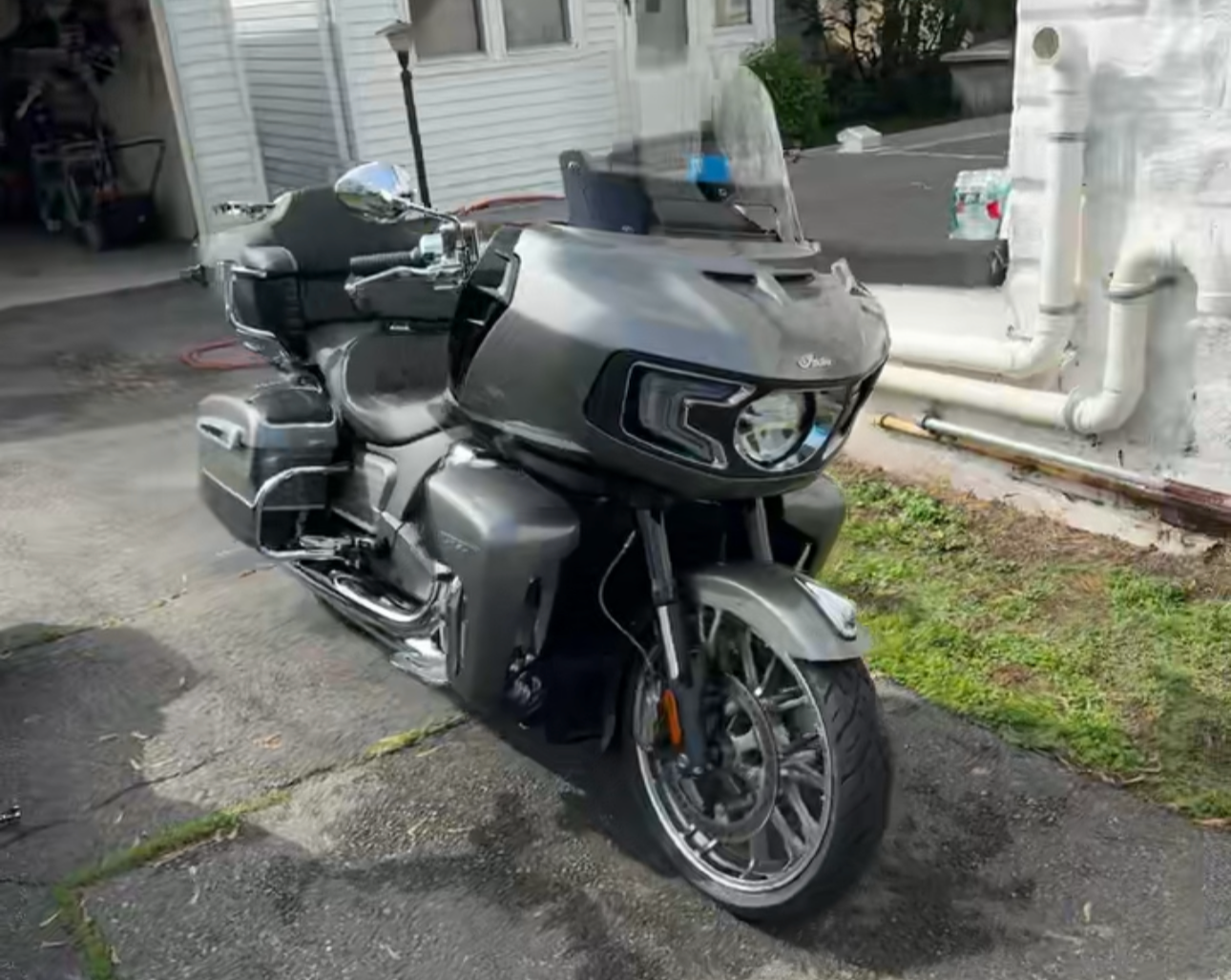 Gray Indian Challenger motorcycle parked on a paved driveway next to a building.