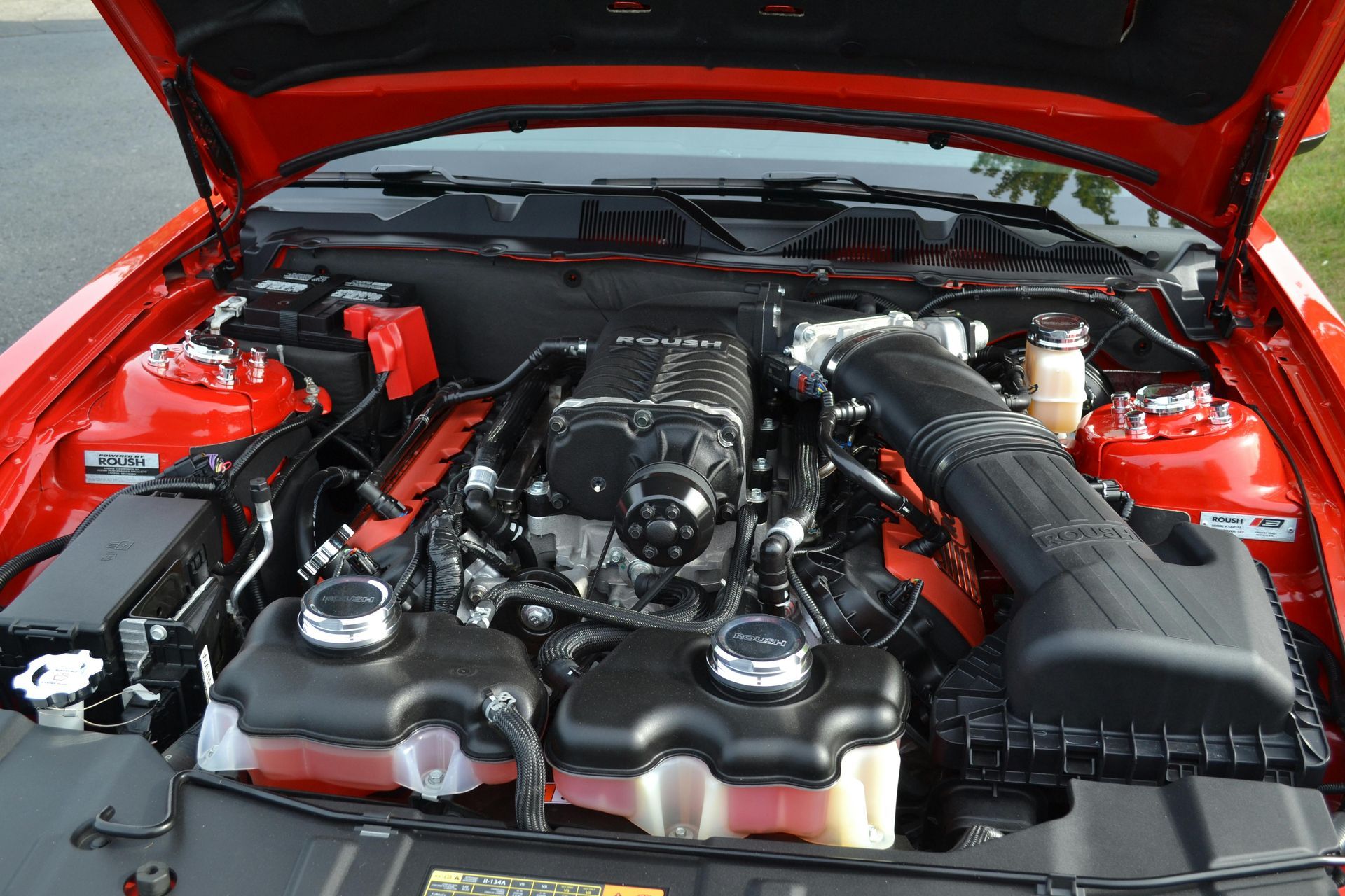 Red car engine with black supercharger and intake.
