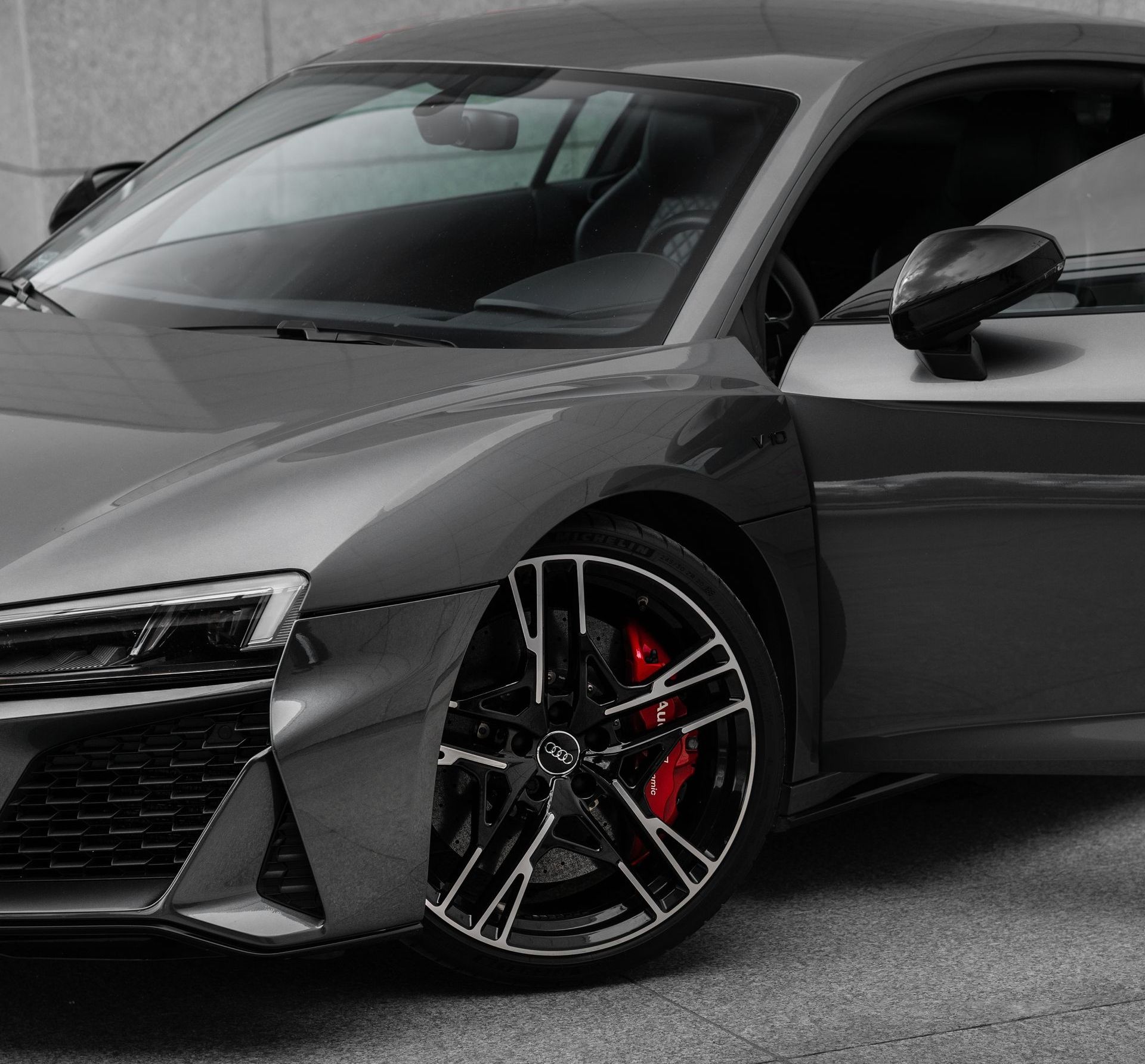 Hand in black glove applying ceramic coating to black car surface.