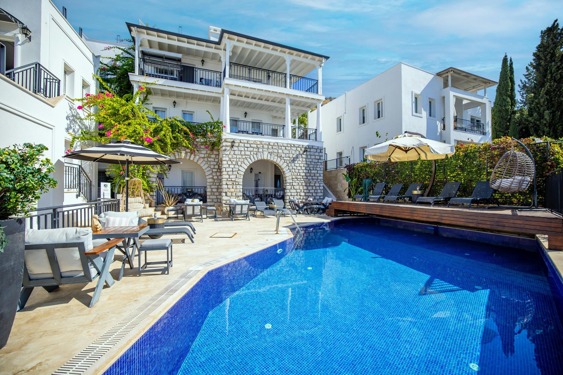 Swimming pool and white buildings with balconies on a sunny day.