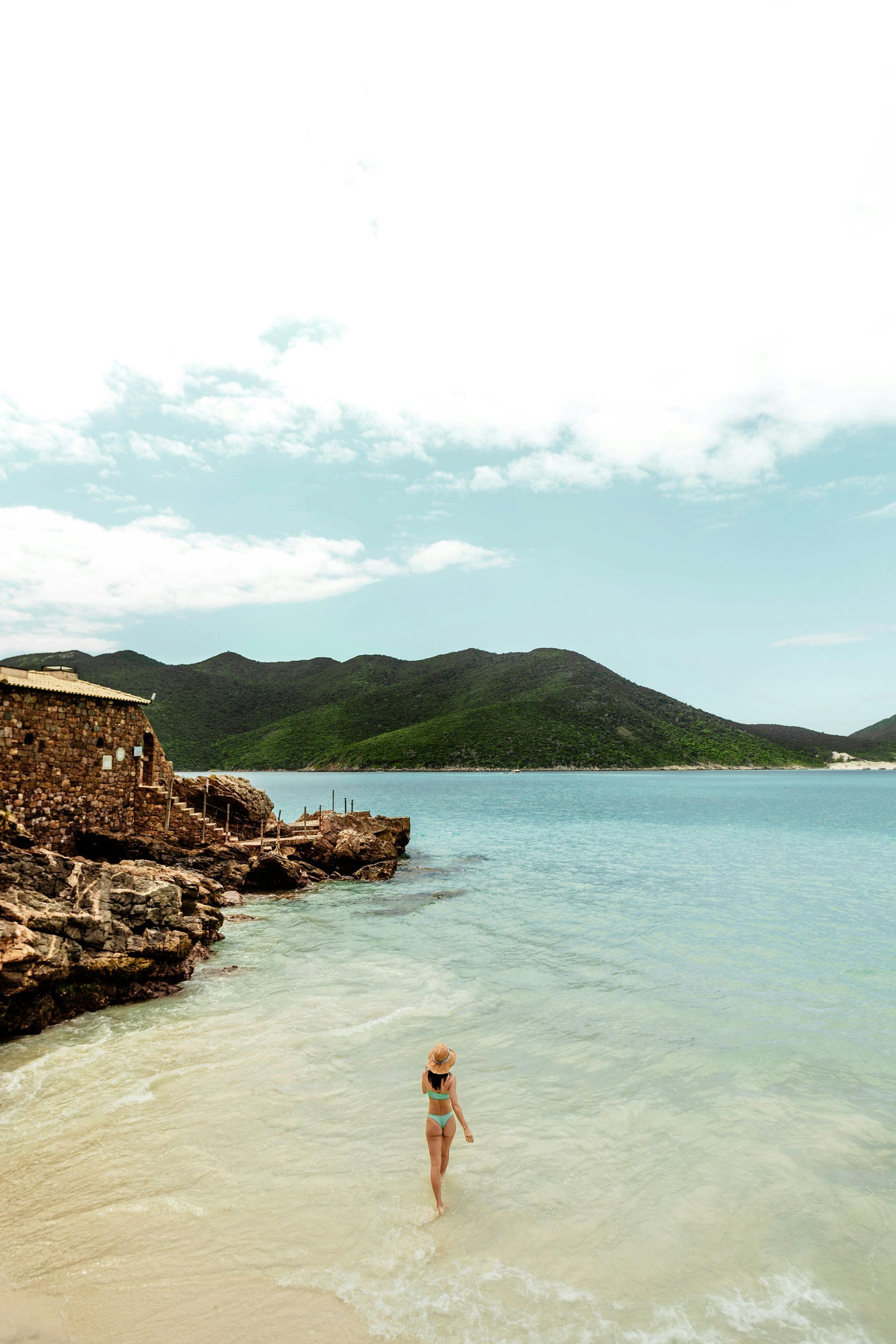 Beach with white sand, turquoise water, and lounge chairs under a blue sky with palm trees.