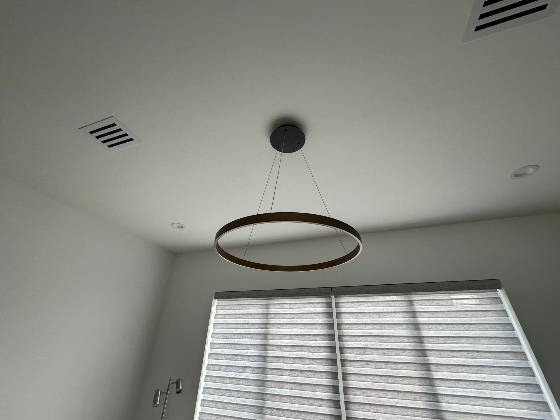 A ceiling light is hanging from the ceiling in a room with blinds.