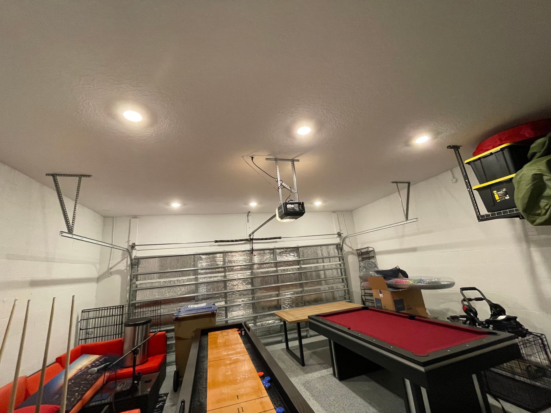 A garage with a pool table and a basketball hoop