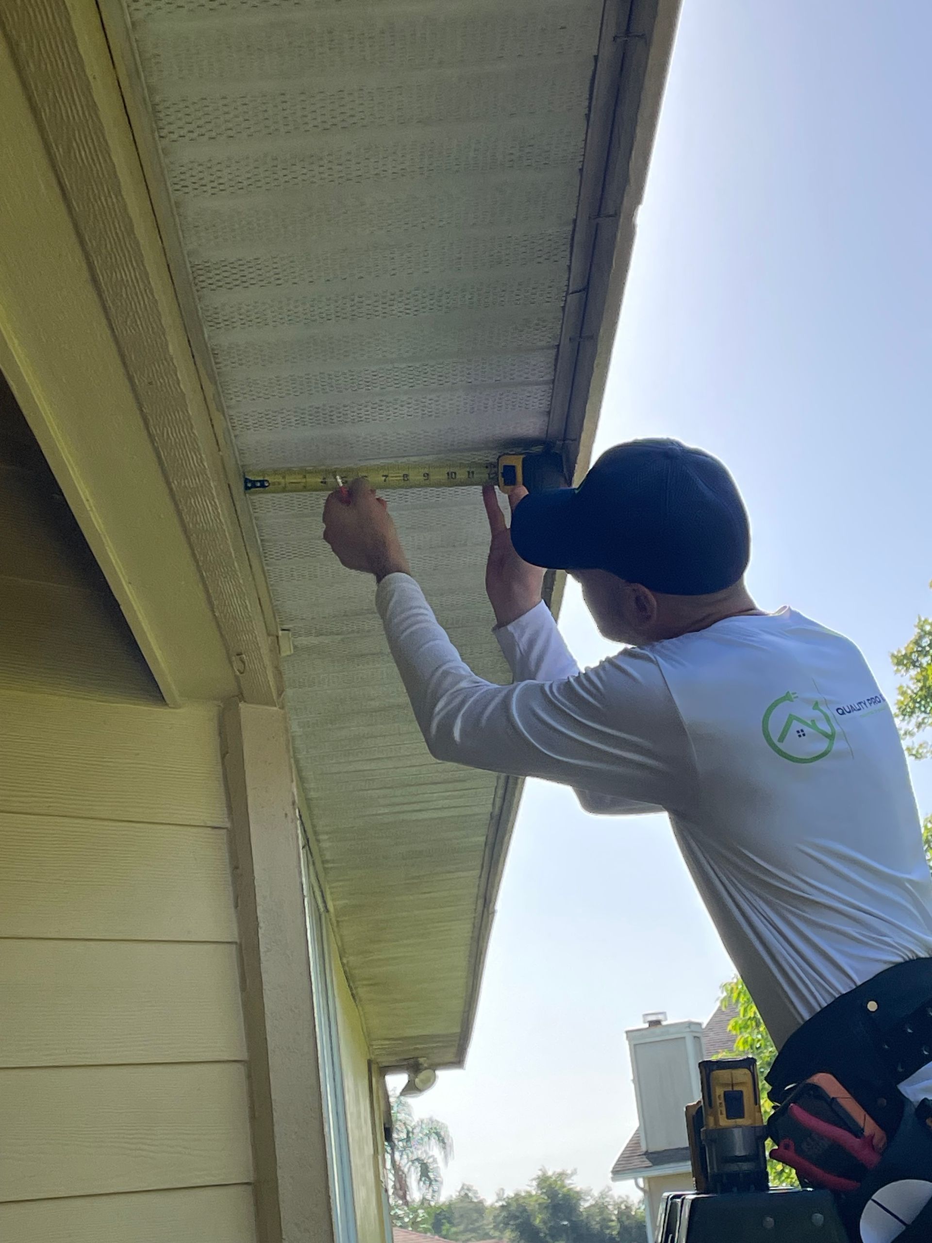 A man is measuring the roof of a house with a tape measure.
