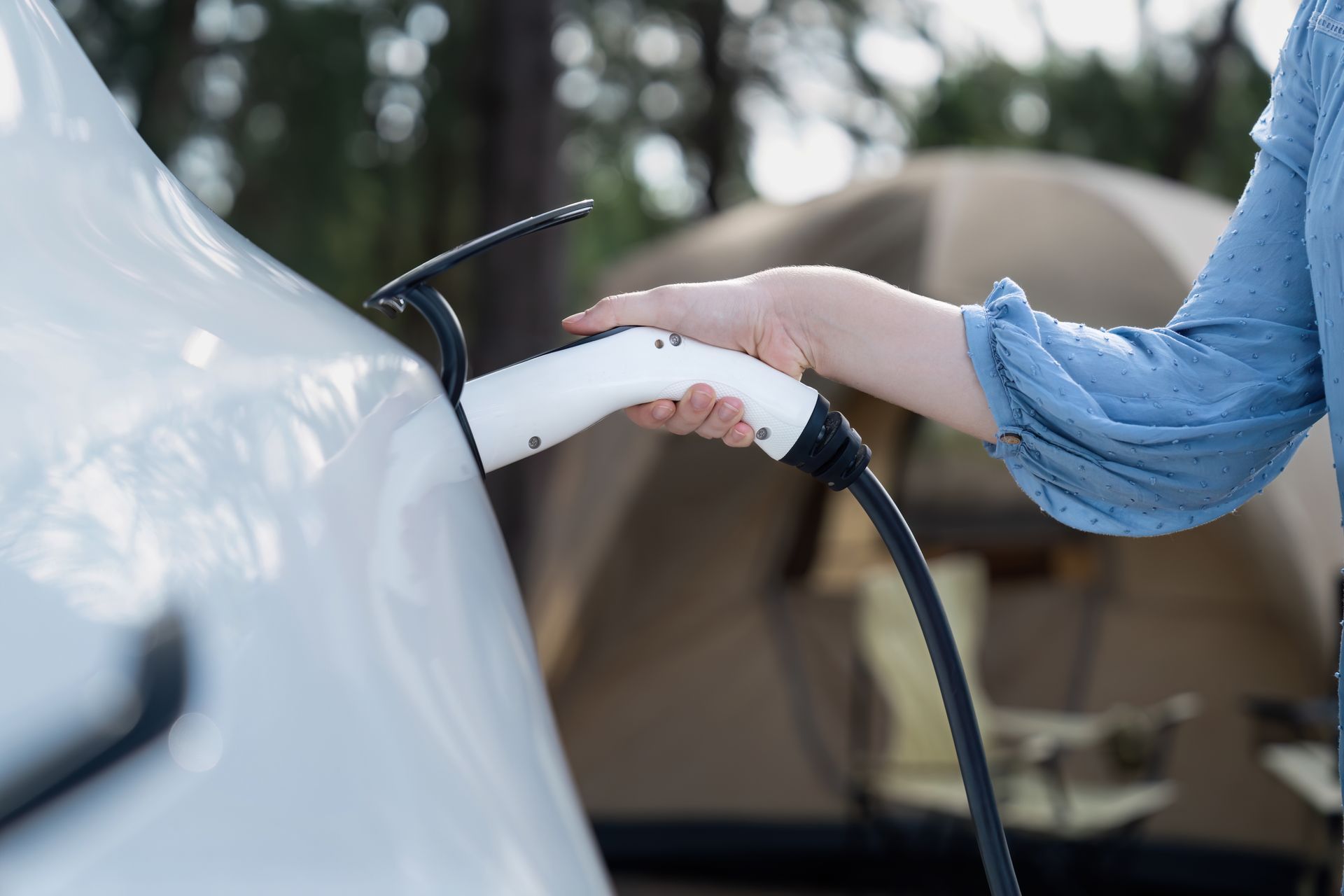 A woman is charging her electric car at a charging station.