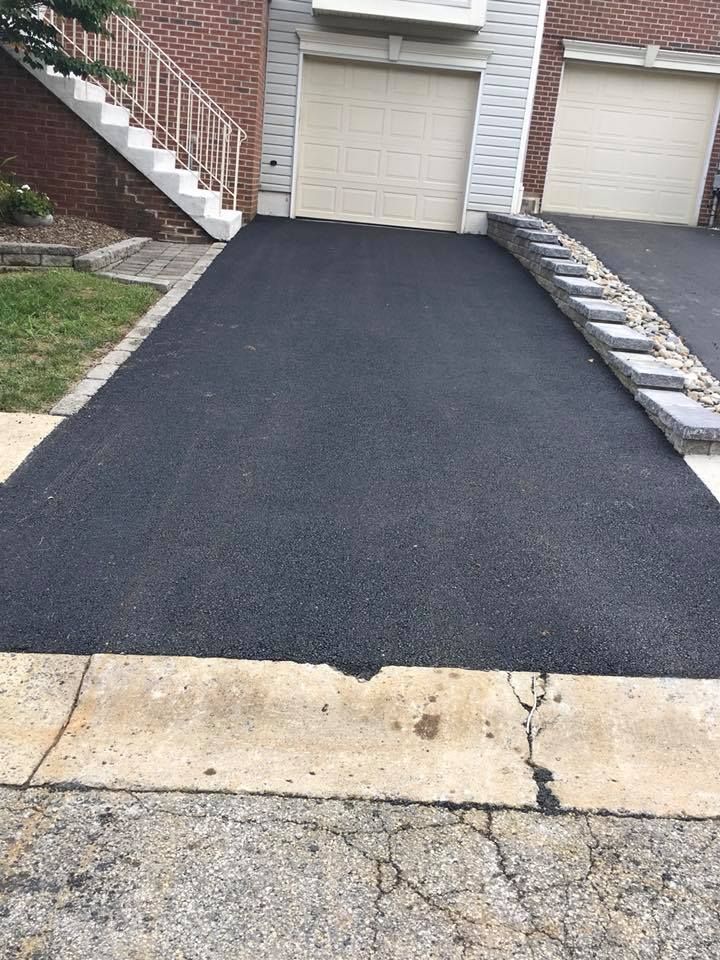 Newly paved black asphalt driveway in front of a house.